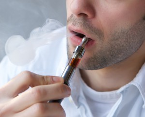 Close up part face of young man exhaling smoke from electric cigarette